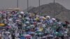 Peregrinos musulmanes usan sombrillas para protegerse del sol para arrojar piedras contra varias columnas en la lapidación simbólica del diablo, el último rito del haj anual, en Mina, cerca de la ciudad sagrada de La Meca, Arabia Saudí, el martes 18 de junio de 2024.