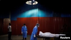 Personal de salud transporta el cuerpo de un hombre fallecido a causa del COVID-19 en Nueva Delhi, India. 