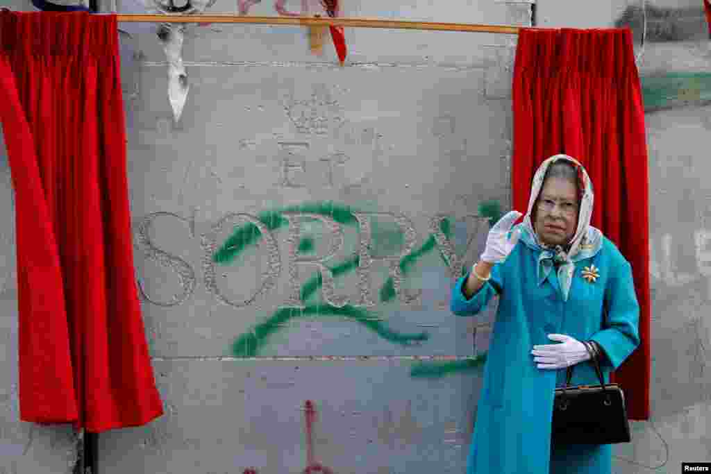 A person, dressed as Britain&#39;s Queen Elizabeth II, gestures during an event ahead of the anniversary of the Balfour Declaration, outside Banksy&rsquo;s Walled Off Hotel in the West Bank city of Bethlehem.
