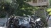 Fuerzas de seguridad afganas inspeccionan los restos de un vehículo de pasajeros después de una explosión en Kabul el 12 de junio de 2021.
