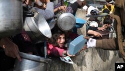 ARCHIVO - Palestinos hacen fila para recibir comida durante la ofensiva aérea y terrestre israelí en curso en Rafah, Gaza, el 9 de enero de 2024.