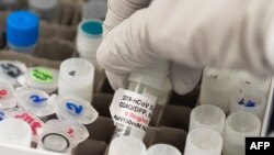 ARCHIVO - Un investigador levanta una ampolla con una posible vacuna contra el COVID-19 en los laboratorios Novavax en Gaithersburg, Maryland, EEUU, el 20 de marzo de 2020, uno de los laboratorios que desarrolla una vacuna contra el coronavirus.