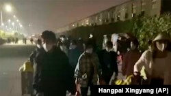 En esta imagen extraída de un video y publicada por Hangpai Xingyang, gente con maletas sale de un complejo de Foxconn en Zhengzhou, en la provincia central china de Henan, el sábado 29 de octubre de 2022. 