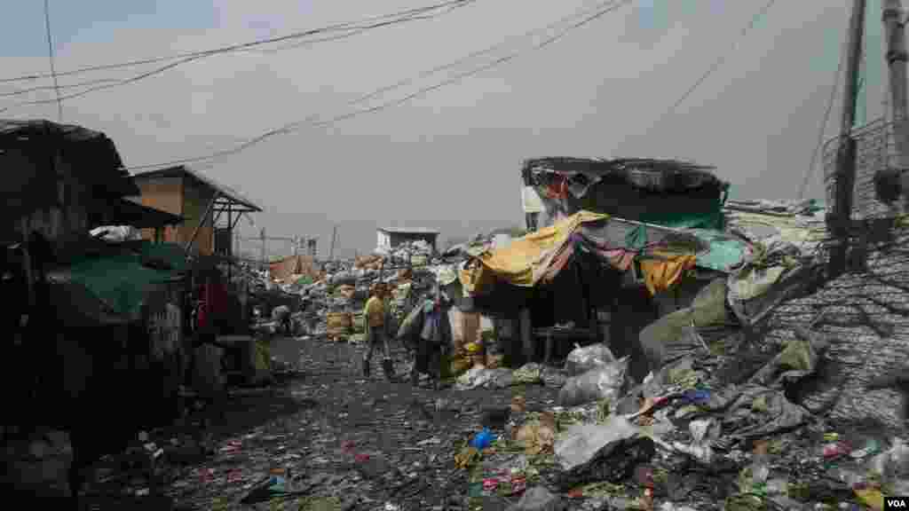 Junk shops line this intersection where scavengers drop off and haul away bags of recyclable material at the Smokey Mountain dump site, Manila Bay, Philippines, Dec. 12, 2013. (Simone Orendain for VOA)