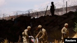 Miembros de la Guardia Nacional de Texas extienden alambradas de púas en cruces de la frontera entre EEUU y México el 13 de mayo de 2023.